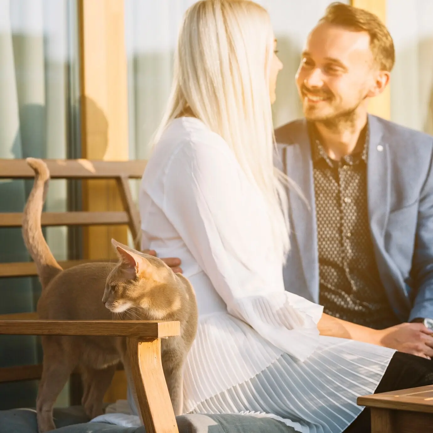 Eine braune Katze steht in der Nähe des liebenswerten jungen Paares, das auf einer Bank sitzt.